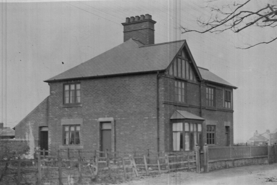 Street scene of a building with bay window surrounded by a wooden fence and brick wall